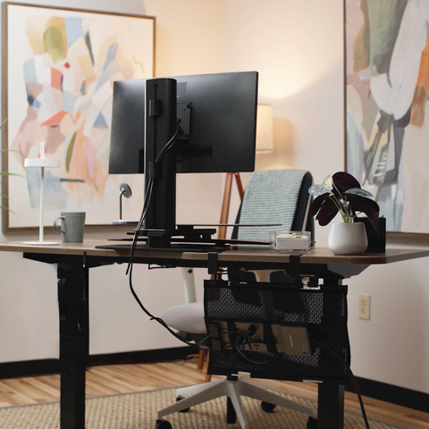 Home office setup with a standing desk, computer monitor, and decor.